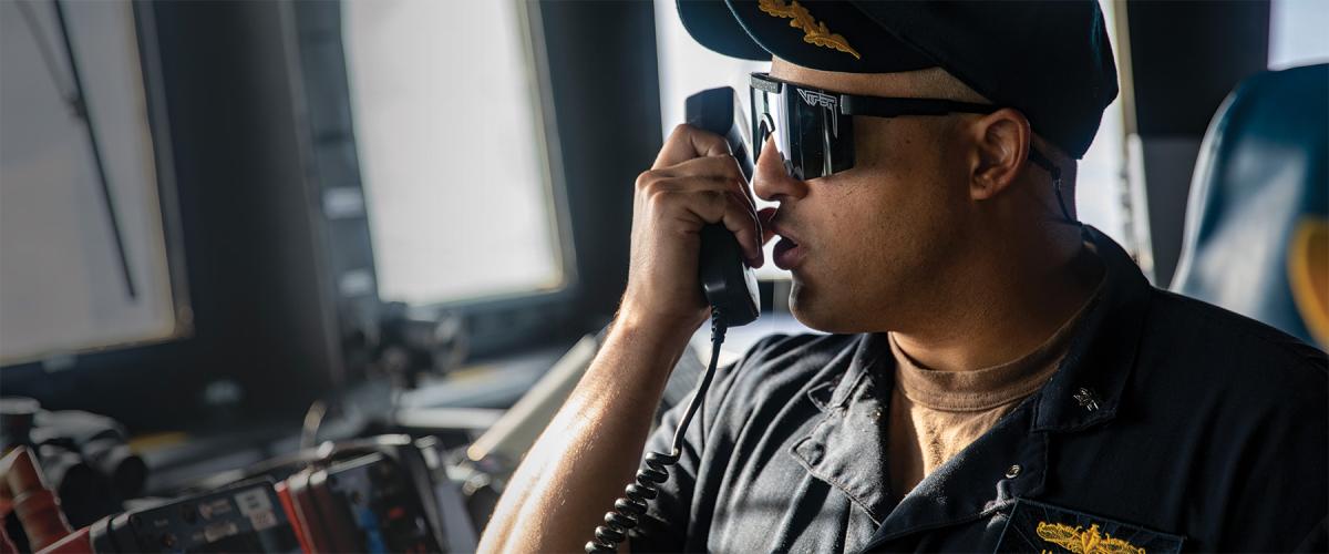 The commanding officer of the Arleigh Burke–class guided-missile destroyer USS Ralph Johnson (DDG-114) communicates with tugboats during a port visit to Guam.