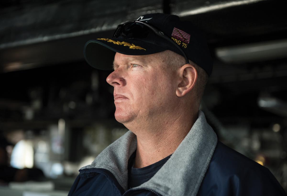 Commanding Officer of the USS Donald Cook (DDG-75) standing on the bridge.