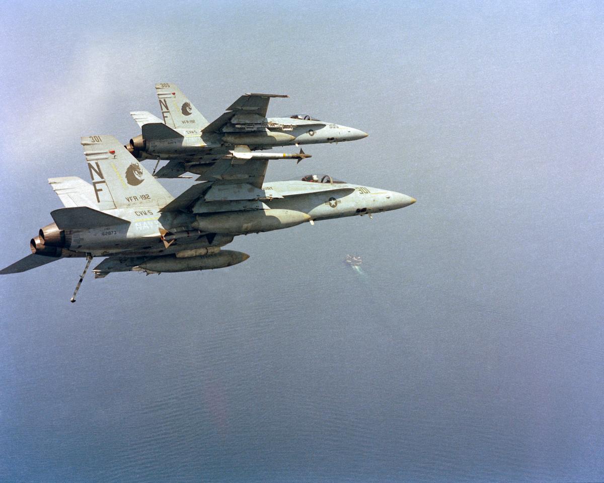 wo F/A-18A Hornet aircraft from Strike Fighter Squadron 192 (VFA-192), bank into a turn to approach the aircraft carrier USS MIDWAY (CV 41).