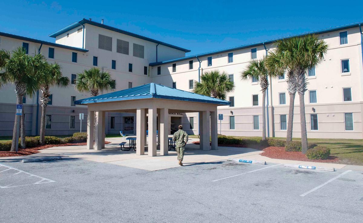 A sailor walks toward Delbert Black Hall, an unaccompanied housing quarters on Naval Station Mayport, Florida. Providing a better quality of life for junior sailors by improving their living quarters could increase retention and productivity.