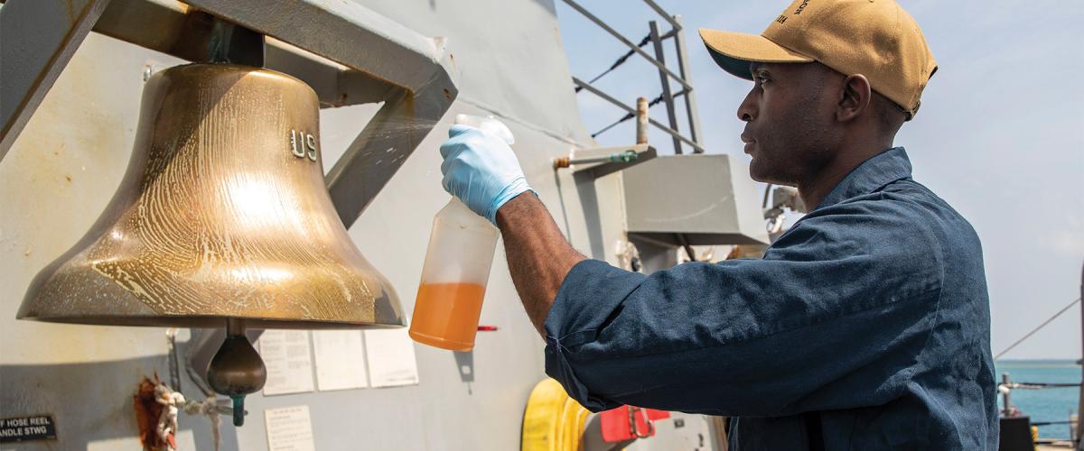 A sailor cleans the ship’s bell on board the USS Ralph Johnson (DDG-114). Engagement can come in many forms, including pride in a sailor’s assigned space.