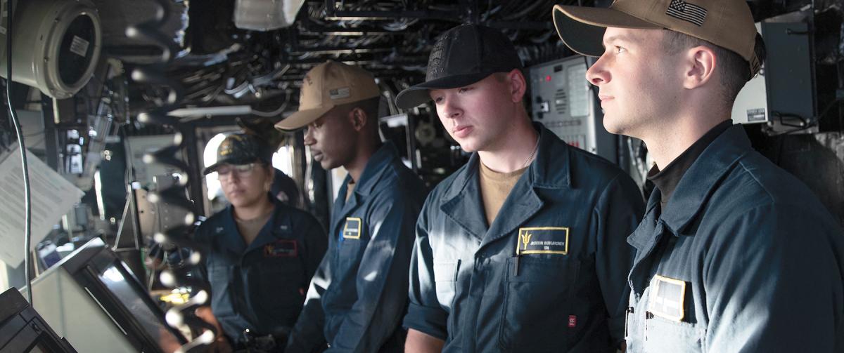 Sailors in working blues on board the USS Tripoli (LHA-7)