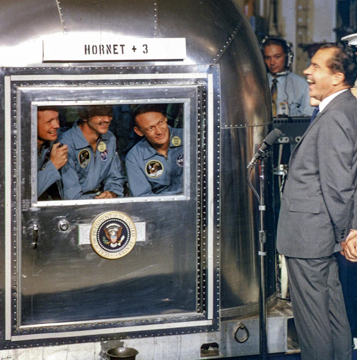 Astronauts in the Mobile quarantine facility aboard USS Hornet greet President Nixon