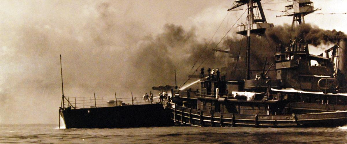 The Hoga battles fires on the battleship Nevada (BB-36) while lashed to the big ship’s bow. She still bears a dent in her hull, allegedly as a result of this event.