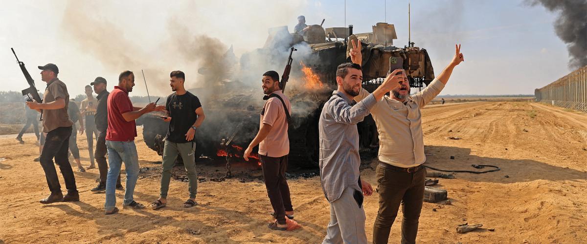 (Above) Palestinians burn an Israeli Merkava battle tank after crossing the border fence with Israel in the Gaza Strip on 7 October 2023. Hackers and catphishers played a vital role in the planning for the Hamas attacks.