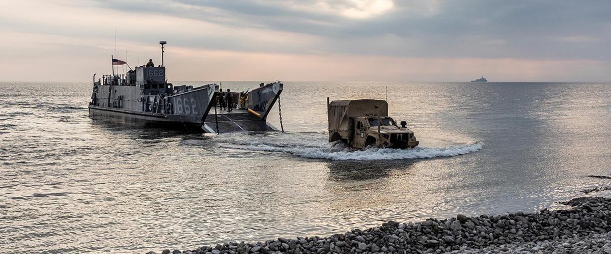 U.S. sailors and Marines come ashore from a landing craft