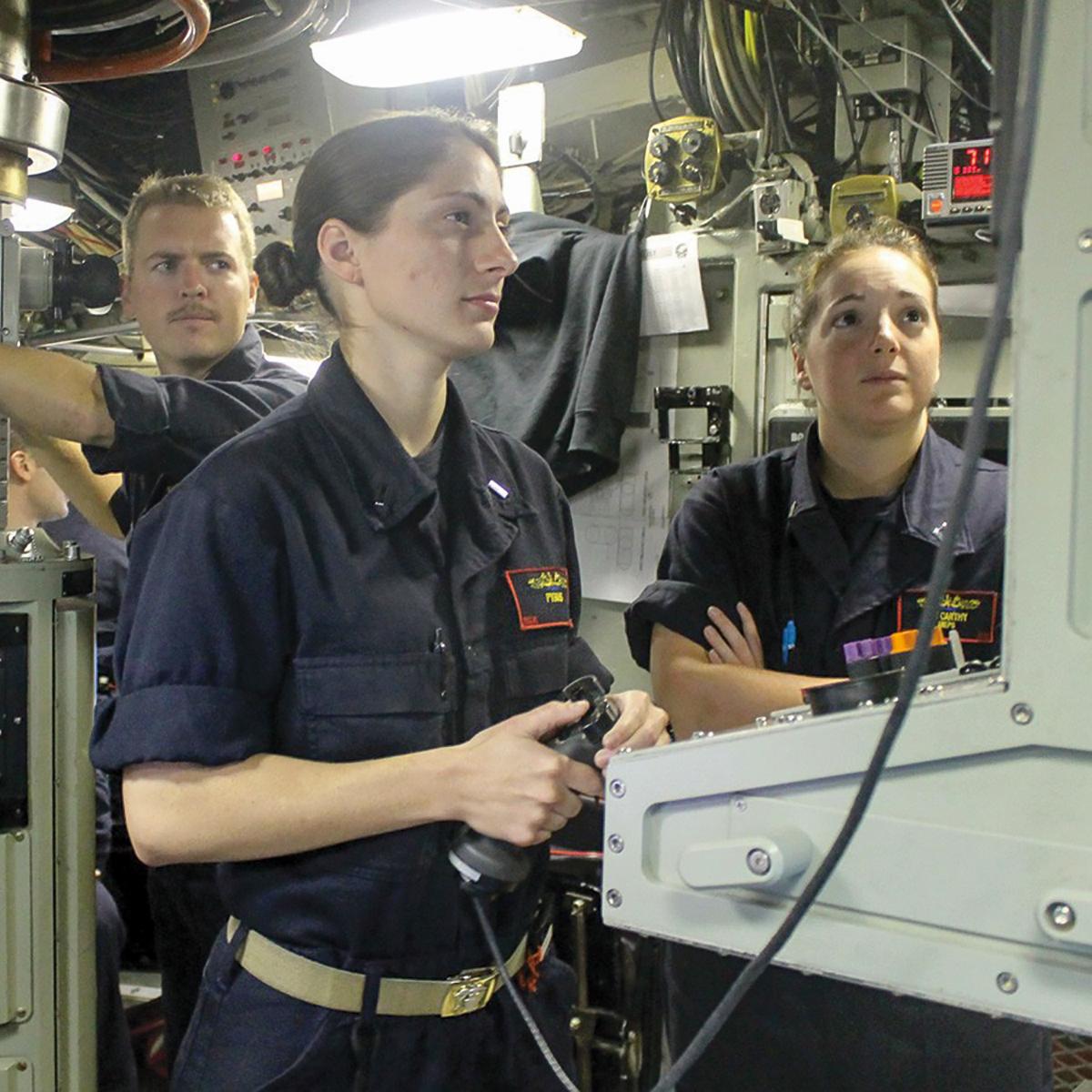 Female submariners standing at a control panel