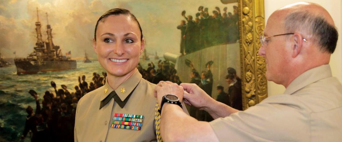 Chief of Naval Operations Admiral Michael M. Gilday attaches the aiguillette to the shoulder of Major Lauren Serrano at the beginning of her tour as his Marine aide-de-camp.