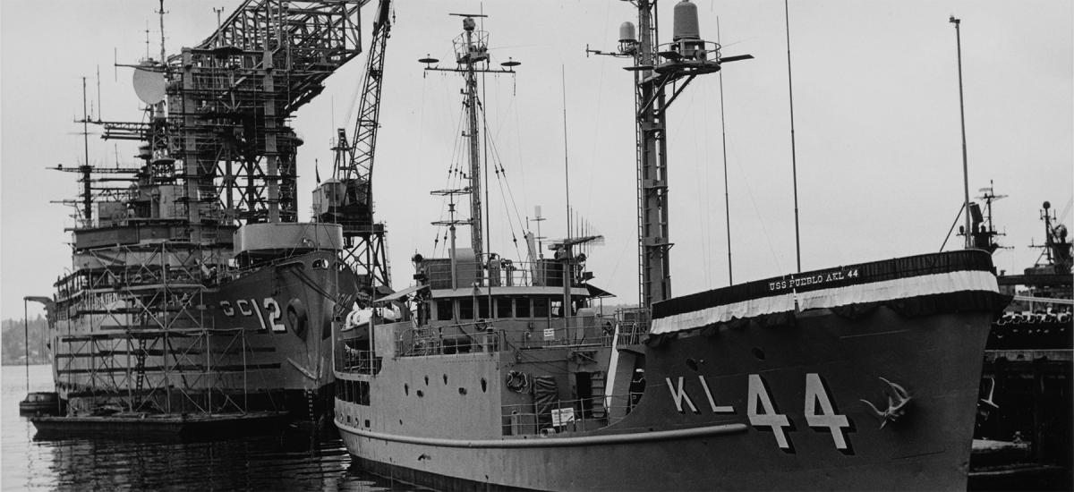Starboard bow view of USS Pueblo (AKL-44) lying at a pier before it was redesignated as USS Pueblo (AGER-2). The 1968 incident highlights the danger of maintaining geographically dispersed defense commitments.