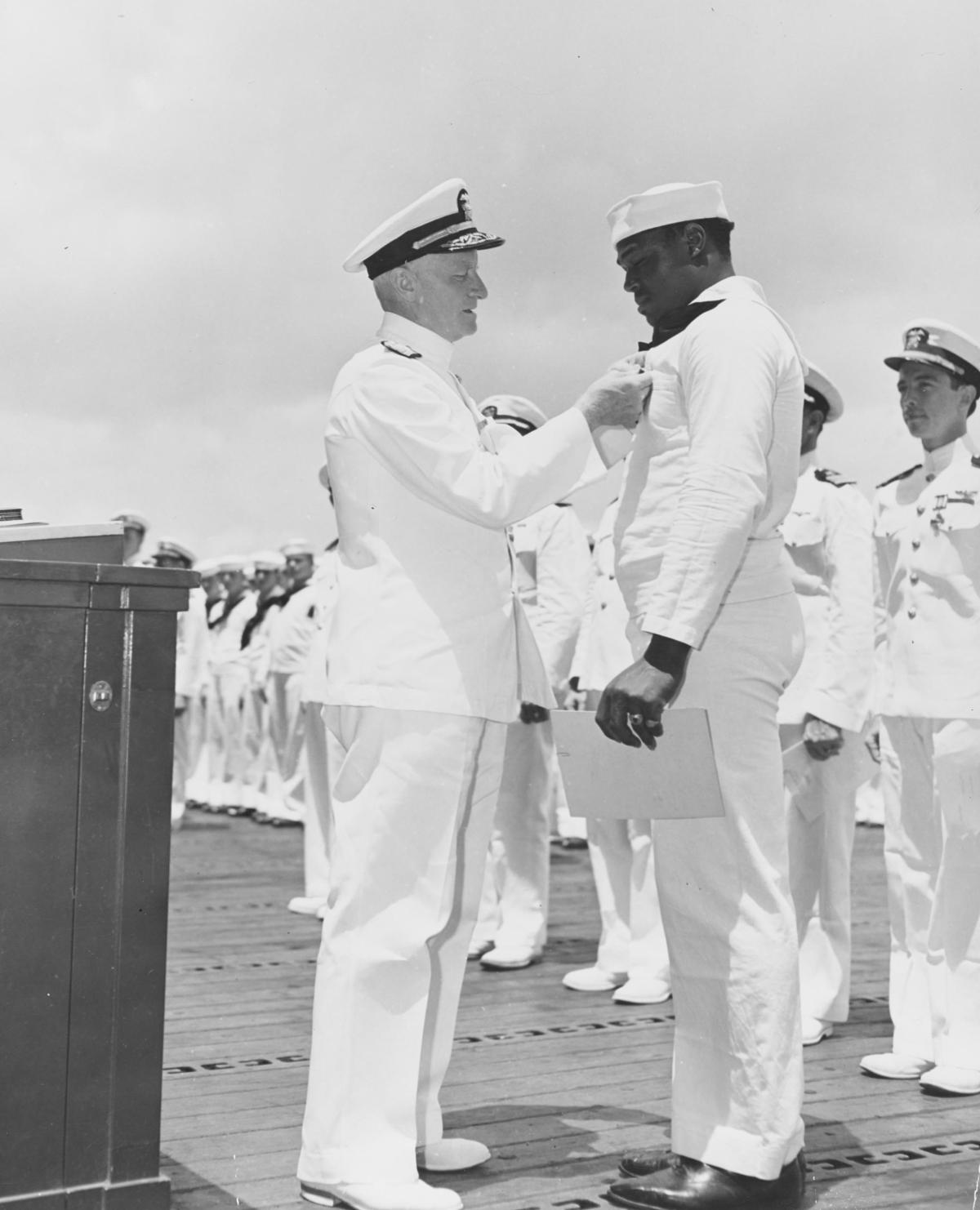 Admiral Chester Nimitz (left) awards the Navy Cross to Messman Third Class Doris “Dori” Miller.