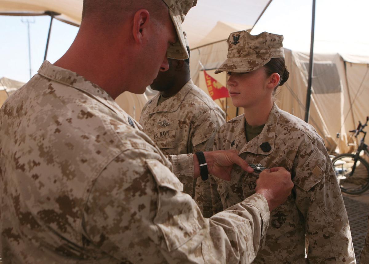 a Navy corpsman is presented with her Fleet Marine Force Warfare Specialist pin during a ceremony