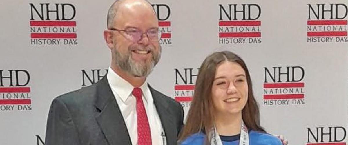High school junior Claire Flynn, an avid participant in National History Day since she was in the sixth grade, poses with her Coskey Naval History Prize alongside  Chip Wallen, Chief Financial Officer of the U.S. Naval Institute, which now sponsors the prize.
