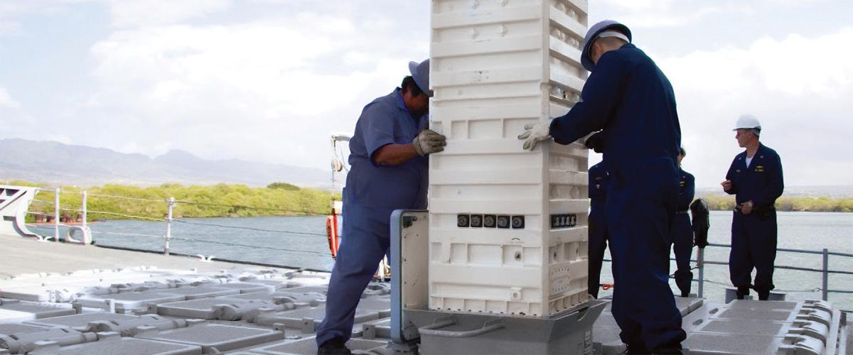 Sailors load a missile cannister into a Mk 41 vertical launch cell.