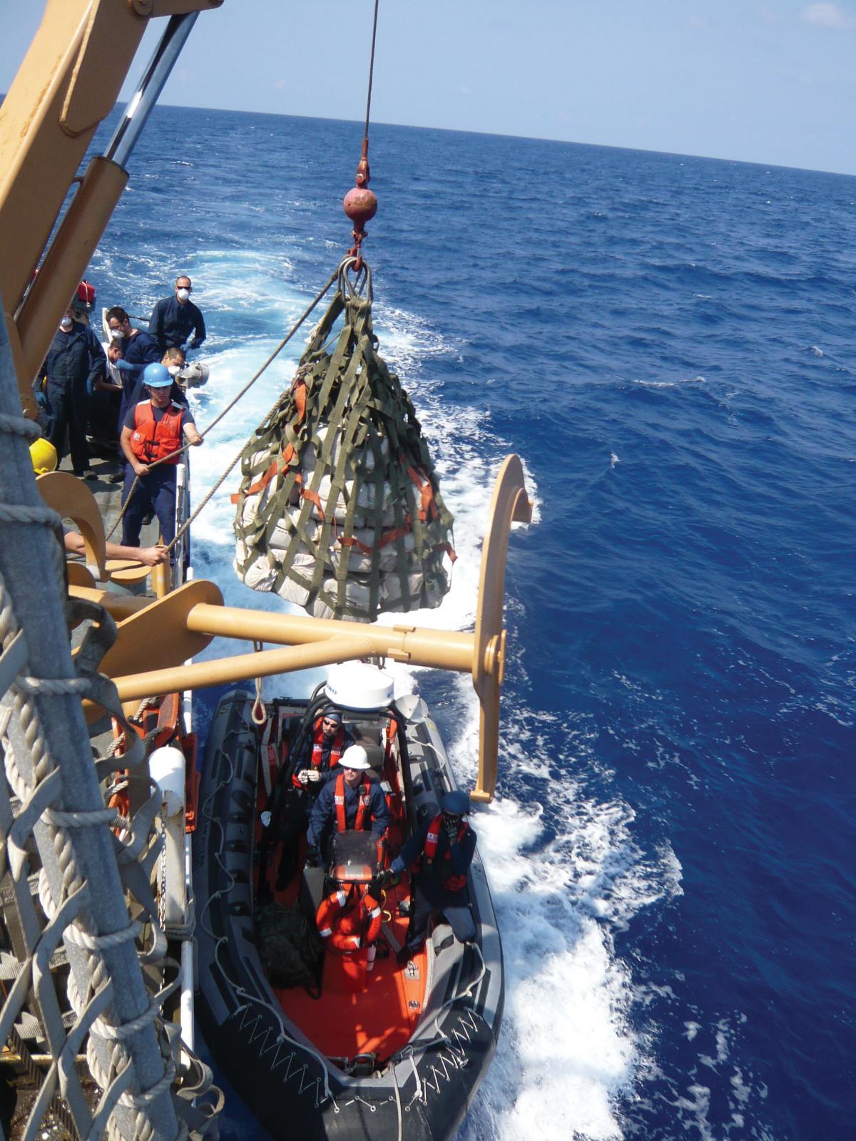 The crew of the Coast Guard Cutter Campbell lowers cocaine onto the small boat of the Coast Guard Cutter Dallas during a transfer of contraband while on patrol in the Caribbean Sea
