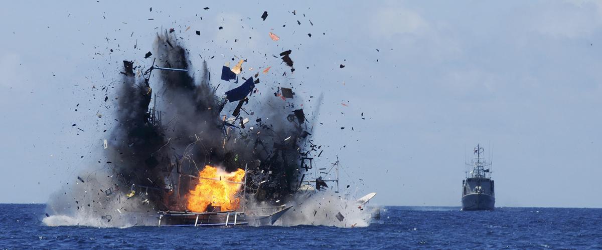 An Indonesian Navy vessel watches as a foreign boat caught fishing illegally in Indonesian waters near Bitung, North Sulawesi, is blown up. As recently as 2019, Indonesia has destroyed fishing boats found violating its exclusive economic zone.
