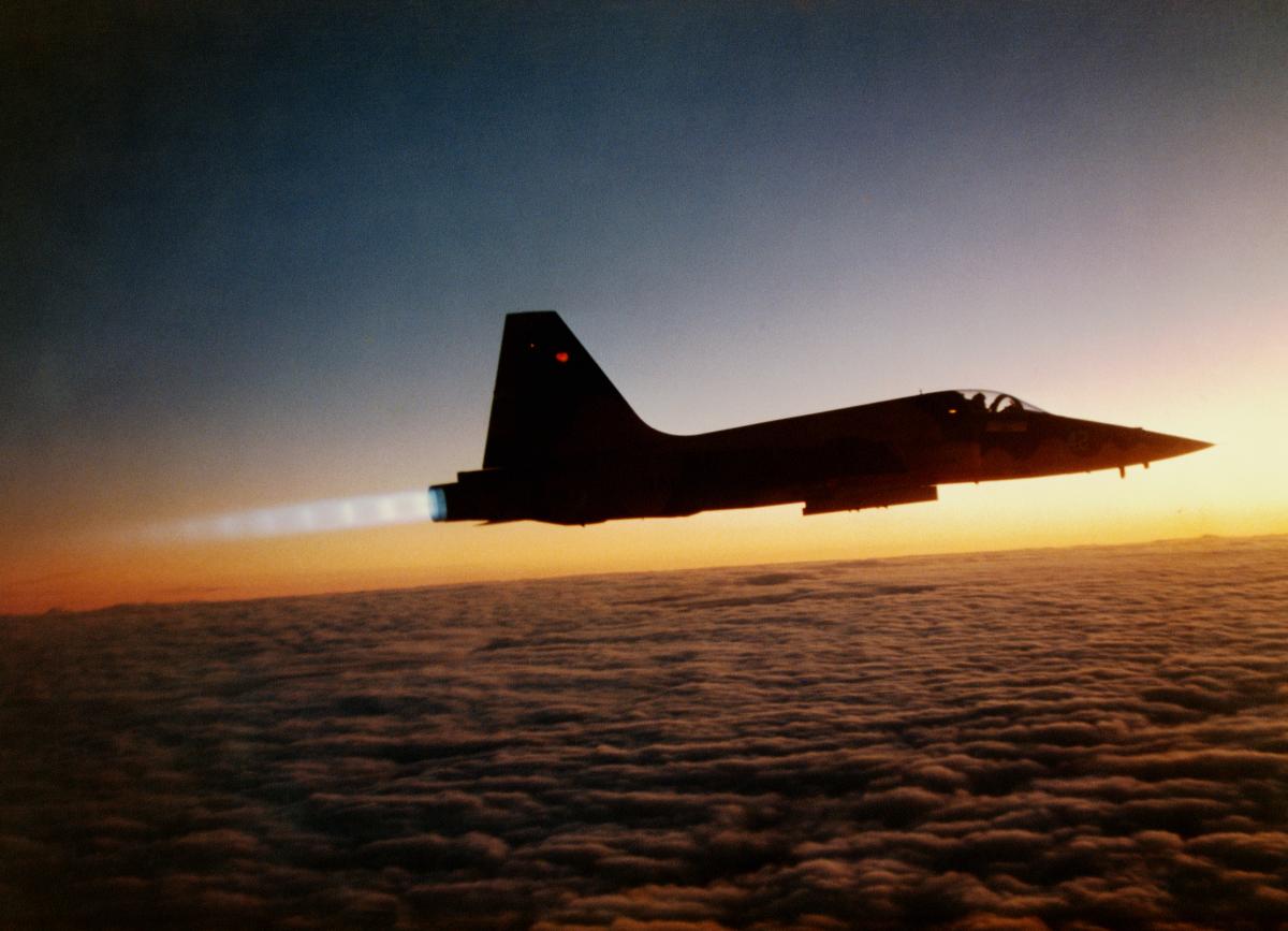 A Navy F-5 in afterburner at sunset