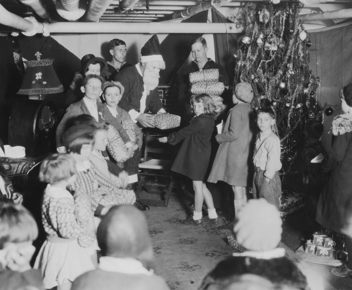 A seagoing Santa Claus distributes presents to children aboard the USS Antares (AG-10) on Christmas day, 1931.