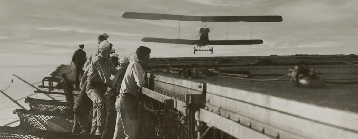 USS Langley sailors look on, an Aeromarine 39-B approaches the carrier’s flying deck