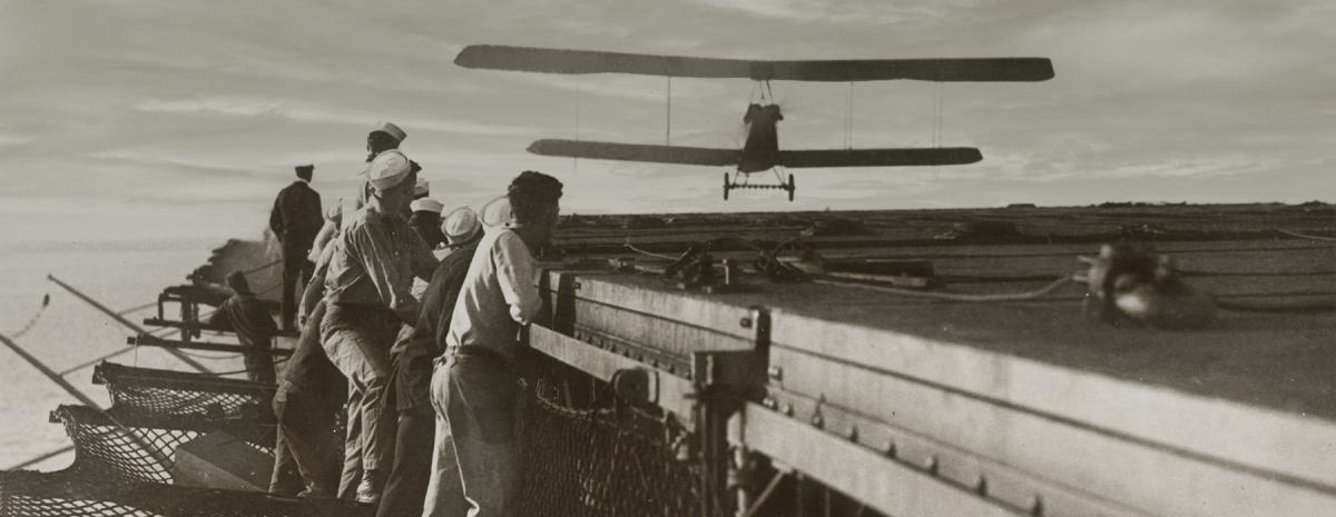 USS Langley sailors look on, an Aeromarine 39-B approaches the carrier’s flying deck
