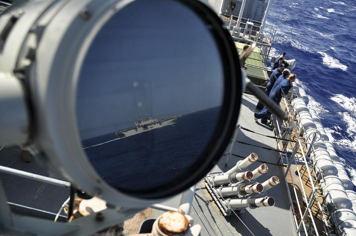A U.S. Navy LHD reflected in the signal lamp of the USS Ponce.