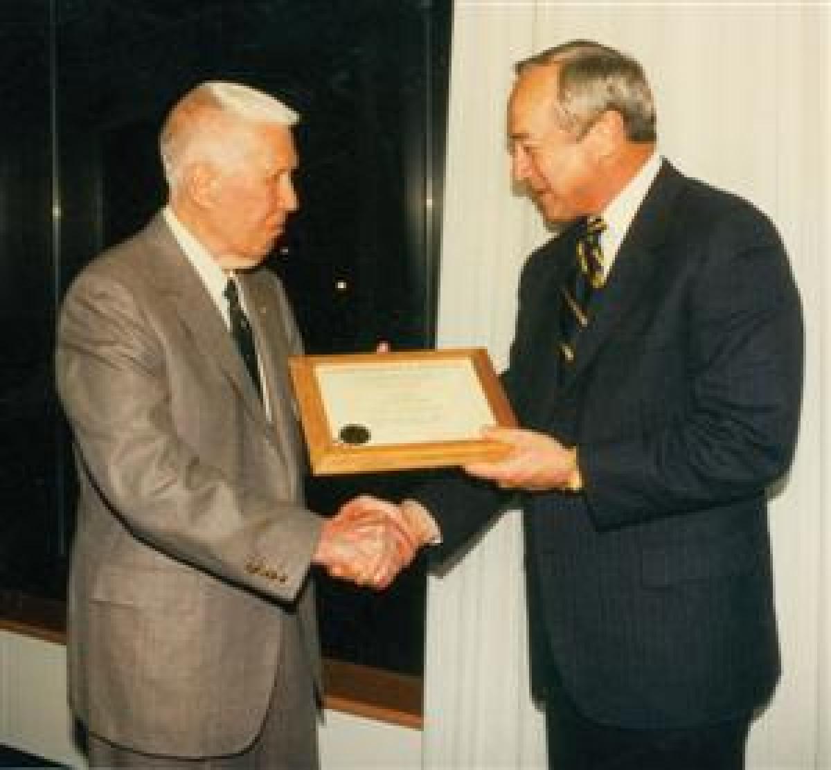 Secretary of the Navy John Dalton, right, congratulates Brast Thomas on becoming a Naval Institute Commodore in April 1996.