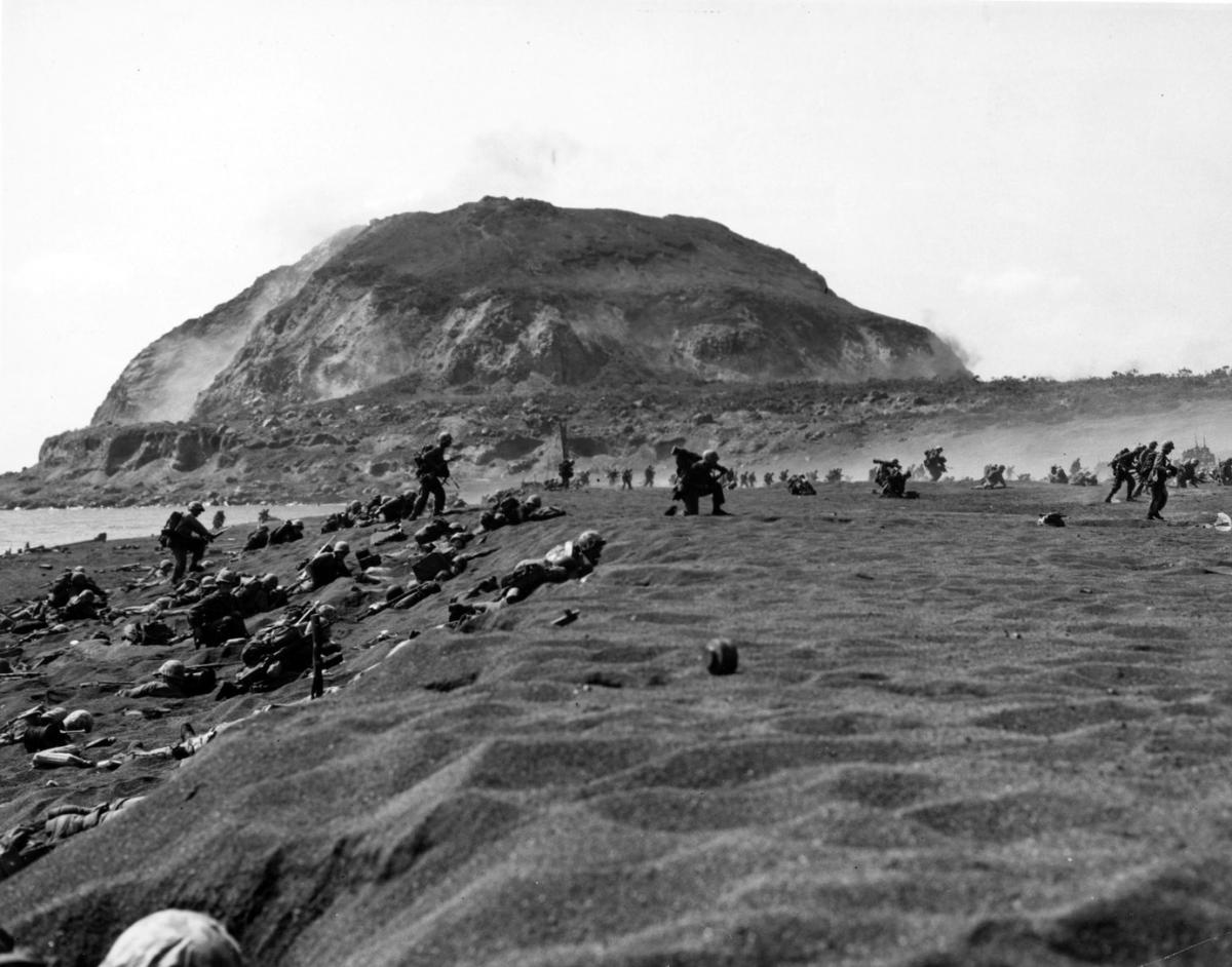 Marines advance in the shadow of Iwo Jima's Mount Suribachi