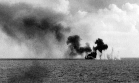 Shells from Japanese cruisers land near the burning escort carrier Gambier Bay during the Battle off Samar on the morning of 25 October 1944