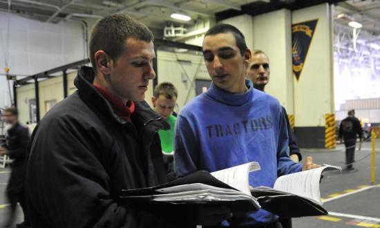 Two aviation boatswain's mates look through their PQS books