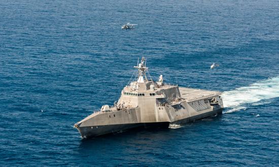 Aerial port bow view of USS Coronado (LCS-4) conducting flight ops with an MH-60 Seahawk helicopter and an MQ-8C Firescout drone