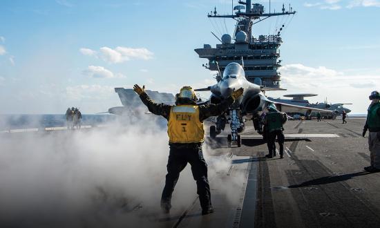 aviation handler directs the pilot of a French Rafale F-3R on the flight deck