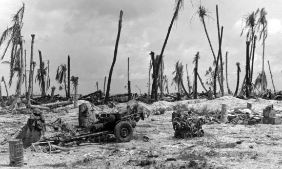 Marine packs and helmets hang from the barrel of a lone 37-mm gun on Tarawa
