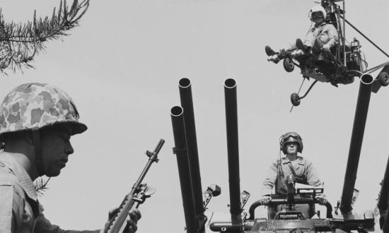 A Marine infantryman (foreground) with M-14 rifle, the operator of an ONTOS antitank vehicle, and a YRON-1 helicopter and its pilot in 1960.
