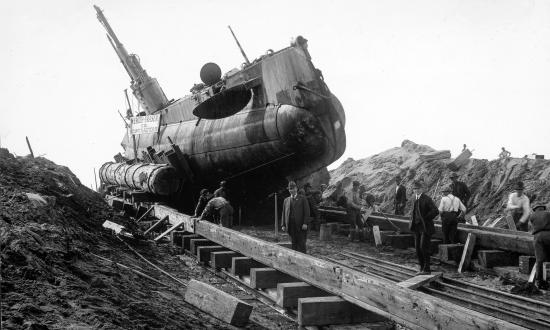 Starboard bow view of submarine USS H-3 on a wooden cradle after being beached.