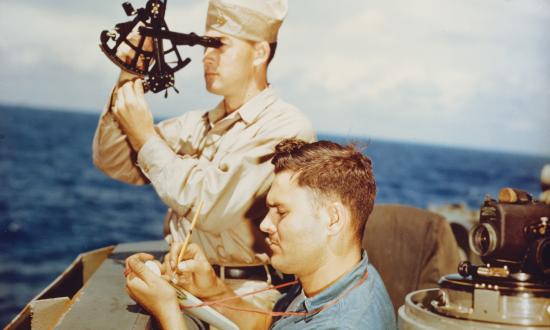 A quartermaster takes a sun sighting from the navigation bridge of the USS Alaska (CB-1) in 1945.