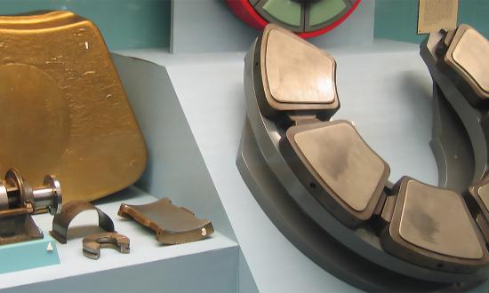 Thrust blocks are specialized bearings that transmit thrust from the propeller shaft to the ship’s hull. The large horseshoe thrust block comprises a set of Michell thrust pads, like those on the 1,000-ton cargo steamship SS Orchy in 1930. The single large gold-colored pad is a wooden model of one of the pads fitted to the battlecruiser HMS Hood.