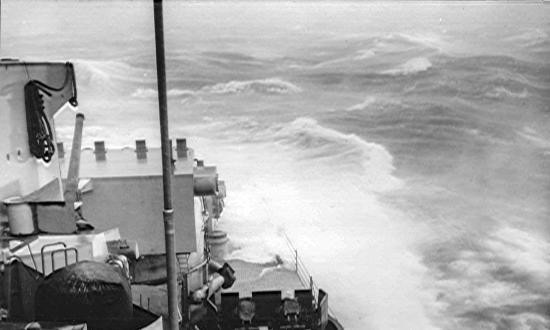 Roiling 100-foot waves tower over what’s left of the forward part of the USS Pittsburgh (CA-72)