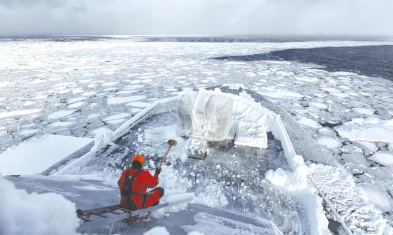 A coast guardsman chips ice on board the Royal Norwegian Coast Guard offshore patrol vessel NoCGV Svalbard.