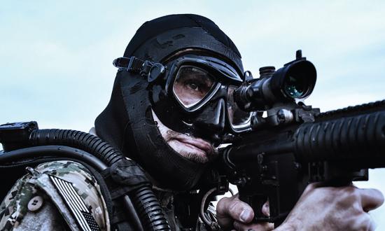 SEAL standing in water holding an automatic rifle