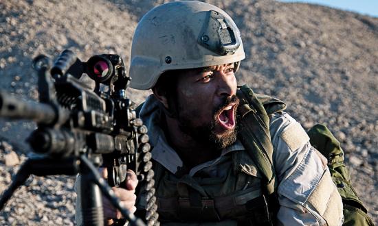 Marine lying prone in a desert with a sniper rifle