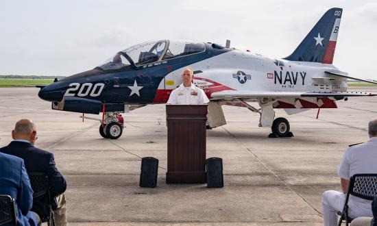 Captain Aaron Rybar, Commander, Training Air Wing - 2, addresses the crowd during a commemorative ceremony onboard Naval Air Station (NAS) Kingsville, July 2024. For 2023, CNATRA produced at 102 percent on average across all pipelines. Currently, all pipelines remain “on glideslope” to achieve the elevated target.