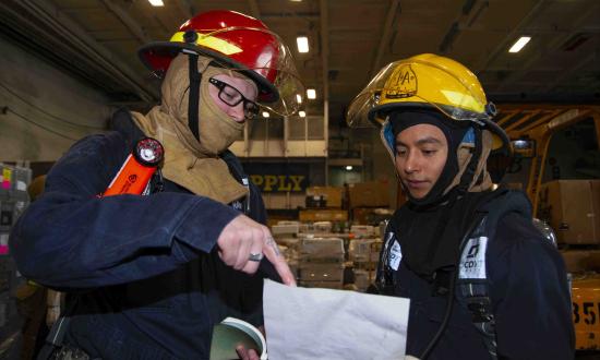 Navy Sailors plan a firefighting exercise onboard ship. 
