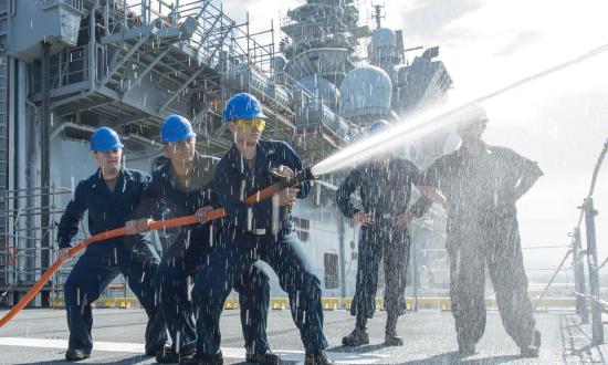 Sailors assigned to the amphibious assault ship USS Makin Island (LHD-8) discharge a firehose over the side as part of damage control trainin