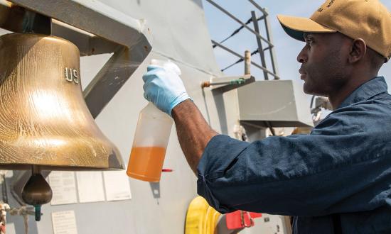 A sailor cleans the ship’s bell on board the USS Ralph Johnson (DDG-114). Engagement can come in many forms, including pride in a sailor’s assigned space.