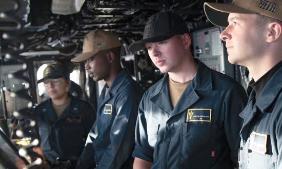 Sailors in working blues on board the USS Tripoli (LHA-7)