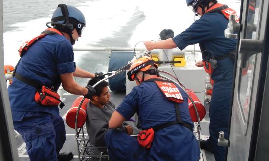 A boat crew from Coast Guard Station Bellingham, Washington, prepares an injured diver to be hoisted from the deck of a 45-foot response boat—medium into an MH-65 Dolphin helicopter after he suffered a diving accident near Patos Island.