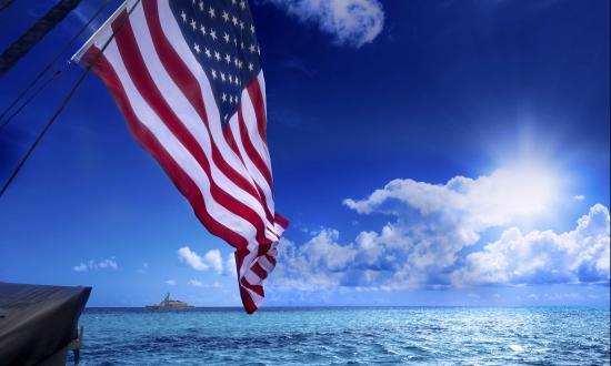 American flag waving over a sunlit sea