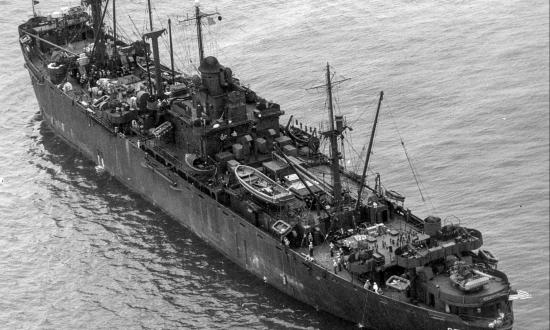 Aerial oblique stern quarter view of the USS Indian Island (AG-77) at anchor