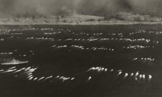 Against the backdrop of a wall of smoke from a massive naval barrage, amphibious tractors ferry U.S. Marines to Iwo Jima landing beaches on D-Day, 19 February 1945.  Devastating naval gunfire, air bombardments, and artillery fire were key elements of the victory at Iwo.