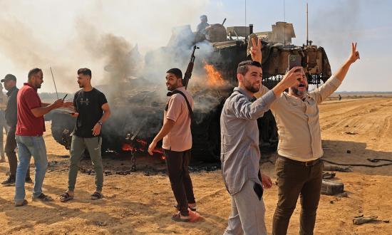 (Above) Palestinians burn an Israeli Merkava battle tank after crossing the border fence with Israel in the Gaza Strip on 7 October 2023. Hackers and catphishers played a vital role in the planning for the Hamas attacks.