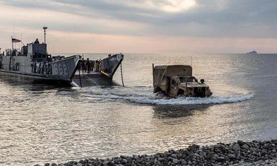 U.S. sailors and Marines come ashore from a landing craft